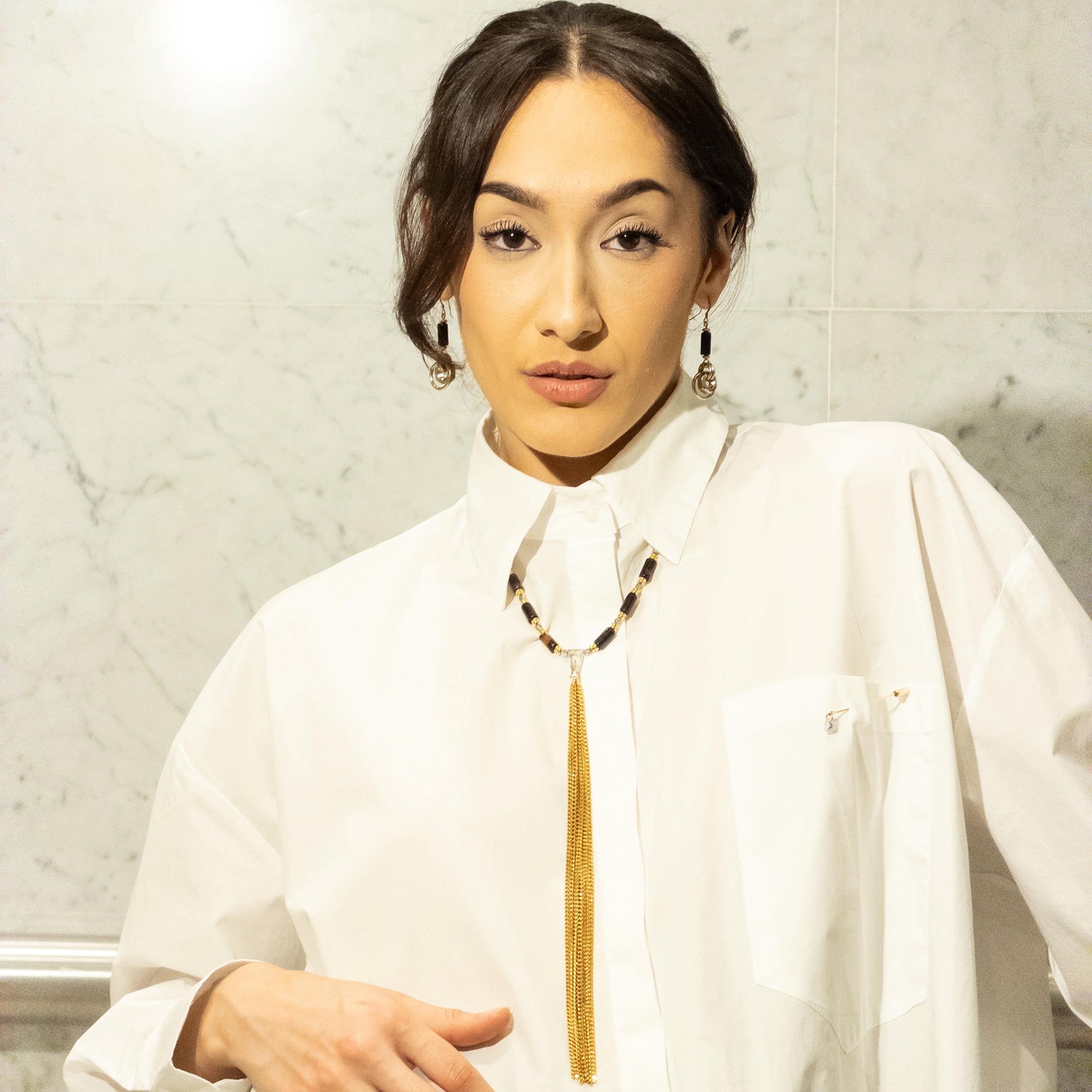 A woman in an architectural white shirt wearing a long Monoxide necklace